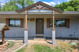 View of front of house featuring crawl space, brick siding, and a porch