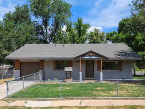 View of front facade with a fenced front yard, an attached garage, driveway, and brick siding