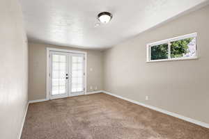 Unfurnished room featuring french doors and carpet