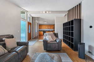 Living room with light carpet, a textured ceiling, and beverage cooler
