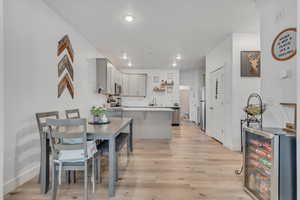 Dining space with wine cooler, light wood-style flooring, and recessed lighting
