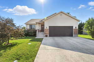 Ranch style home with driveway, brick siding, a front yard, and a garage
