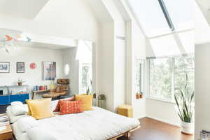 Bedroom with wood finished floors and high vaulted ceiling