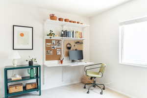 Carpeted home office featuring baseboards