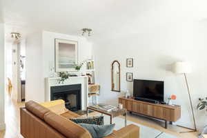 Living area with a textured ceiling, light wood finished floors, and a fireplace