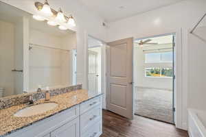 Full bathroom featuring vanity, a shower, wood finished floors, a bathtub, and a ceiling fan