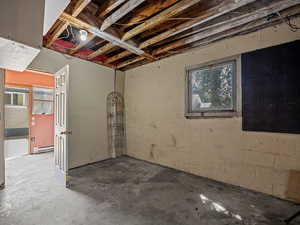 Basement with concrete block wall and a baseboard radiator
