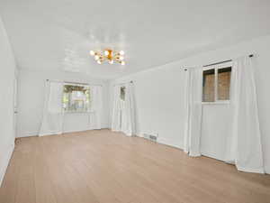 Unfurnished room with a chandelier and light wood-type flooring