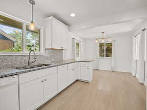 Kitchen with white dishwasher, backsplash, white cabinetry, light stone counters, and recessed lighting
