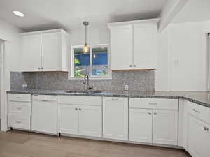 Kitchen with dishwasher, decorative backsplash, white cabinets, and recessed lighting