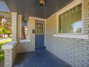 Entrance to property with covered porch and brick siding