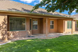 Rear view of property with stucco siding, a patio area, and a yard