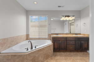 Bathroom with a bath, double vanity, and tile patterned floors