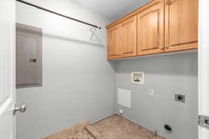 Laundry room featuring hookup for a gas dryer, hookup for an electric dryer, electric panel, cabinet space, and washer hookup