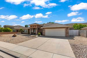 Prairie-style house with stone siding, a garage, concrete driveway, and a tile roof