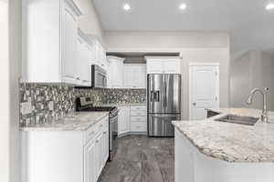 Kitchen with dark marble finish floors, stainless steel appliances, white cabinetry, tasteful backsplash, and recessed lighting