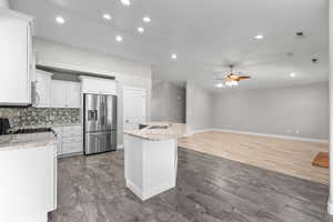 Kitchen with a ceiling fan, appliances with stainless steel finishes, recessed lighting, white cabinetry, and an island with sink