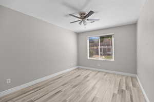 Spare room featuring light wood-style flooring, ceiling fan, and a textured ceiling