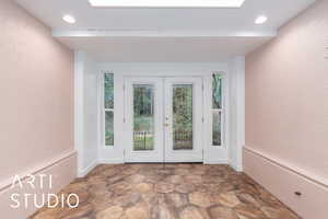 Doorway featuring french doors, stone finish flooring, recessed lighting, and a textured wall