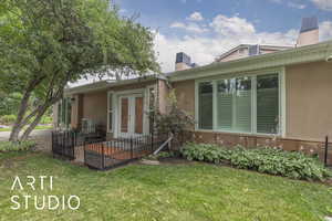 View of front of house with a chimney, french doors, stucco siding, and a front yard