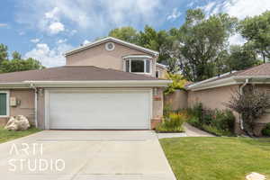 Traditional home featuring concrete driveway, an attached garage, stucco siding, and a shingled roof