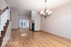 Unfurnished living room featuring light wood-type flooring, stairway, a chandelier, and a premium fireplace