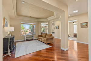 Living room featuring a raised ceiling, a ceiling fan, healthy amount of natural light, and a textured ceiling