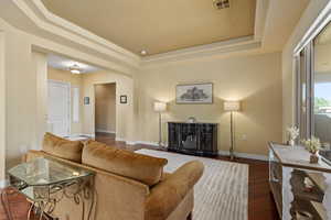 Living area with a raised ceiling, a wood stove, and wood finished floors