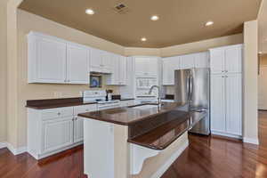 Kitchen featuring white appliances, dark wood finished floors, dark countertops, white cabinetry, and recessed lighting