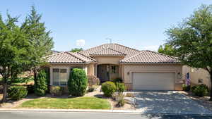 Mediterranean / spanish-style home with a garage, stucco siding, concrete driveway, and a tiled roof