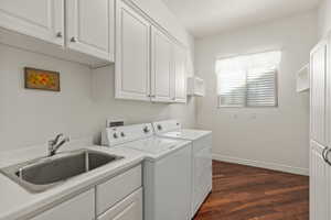 Laundry room with independent washer and dryer, cabinet space, and dark wood-style flooring