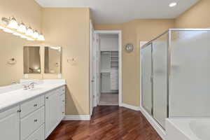 Bathroom with a stall shower, wood finished floors, vanity, and a spacious closet