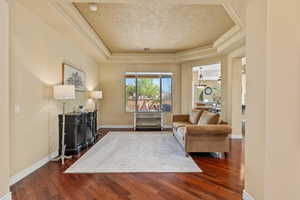 Living area featuring a tray ceiling, wood finished floors, and a textured ceiling