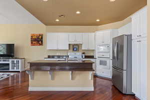 Kitchen featuring dark countertops, dark wood-style floors, white appliances, white cabinetry, and recessed lighting