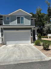 View of front of house featuring an attached garage, concrete driveway, and stone siding