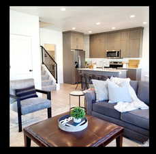 Living room with light wood-style floors, stairway, and recessed lighting