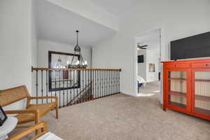 Sitting room with a chandelier, carpet floors, crown molding, an upstairs landing, and ceiling fan