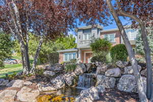 View of front facade featuring a garden pond, brick siding, and a balcony