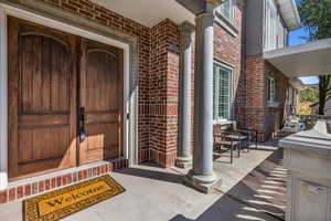 Doorway to property featuring brick siding and a porch