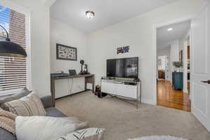 Carpeted living room with recessed lighting and an office area