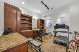 Exercise area with rail lighting and dark stone finish flooring