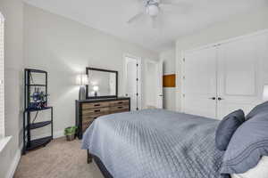 Bedroom with light carpet, a closet, and a ceiling fan