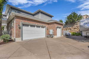 View of side of property with driveway, an attached garage, and brick siding