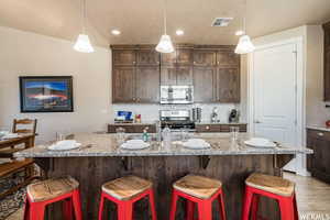Kitchen with stainless steel microwave, gas range, decorative backsplash, a kitchen breakfast bar, and dark brown cabinetry