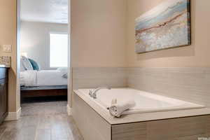 Bathroom with a garden tub, ensuite bath, wood finished floors, and vanity