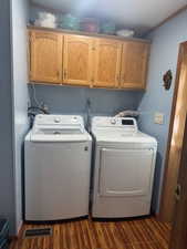 Laundry room featuring cabinet space, washing machine and clothes dryer, dark wood-type flooring, and ornamental molding