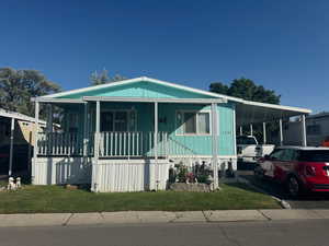 View of front facade with an attached carport, a porch, and a front yard