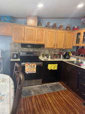Kitchen featuring stainless steel electric stove, light countertops, dishwasher, decorative backsplash, and dark wood-style floors