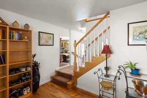 Stairway with wood finished floors and baseboards