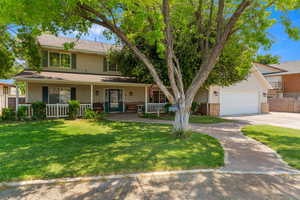 View of front of property with covered porch, concrete driveway, and a front lawn